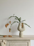 Textured beige ceramic sculptural vase with organic double neck design styled with branches