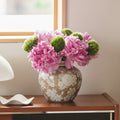Beige and white floral ceramic vase with pink peonies on sideboard