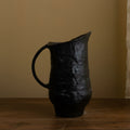 Side view of textured black ceramic pitcher with handle
