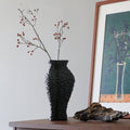 Textured black ceramic vase with red berry branches