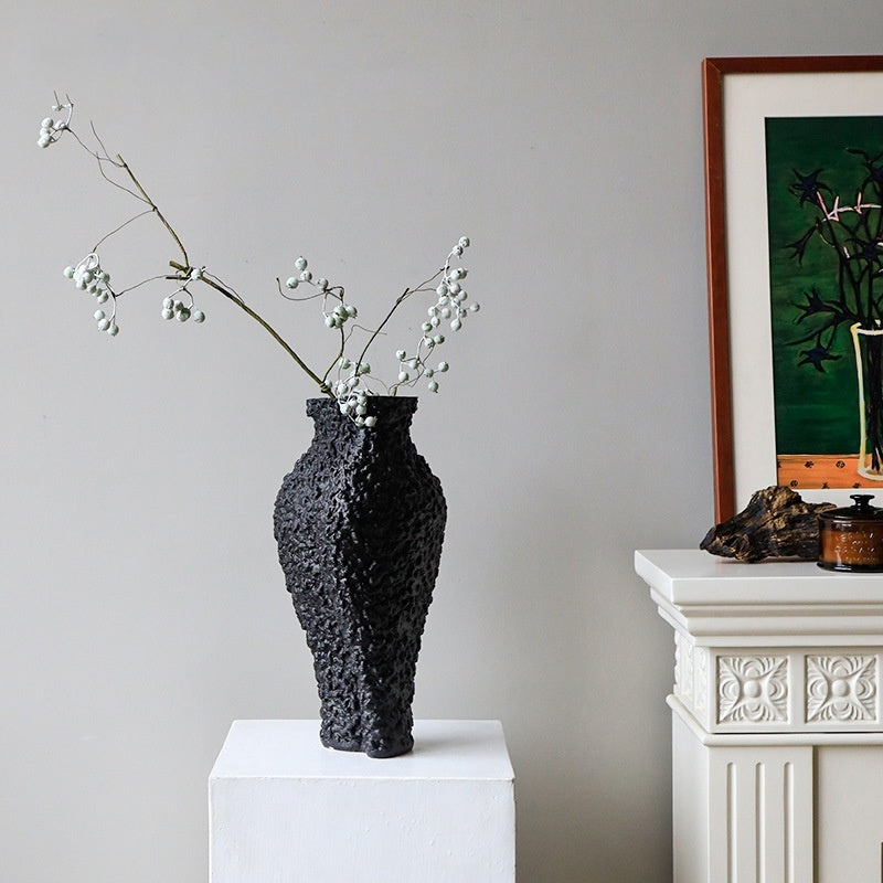 Textured black vase on white pedestal display