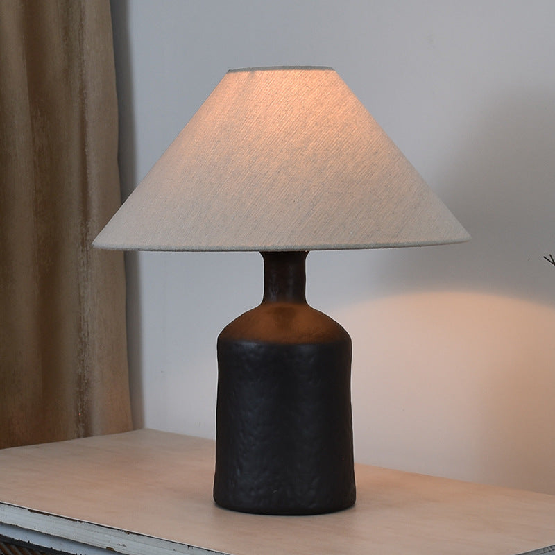 Textured black metal table lamp with conical shade lit