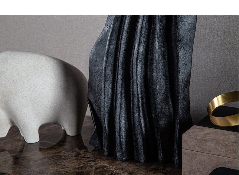 Black sculptural vase on marble table with decor