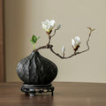Textured black teardrop vase displaying white magnolia branch