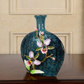 Angled view of blue glass vase with pink enamel orchid detail
