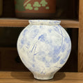 Front view of textured blue and white ceramic globe vase on wooden shelf
