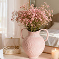 Textured blush ceramic vase filled with pink flowers on a vanity