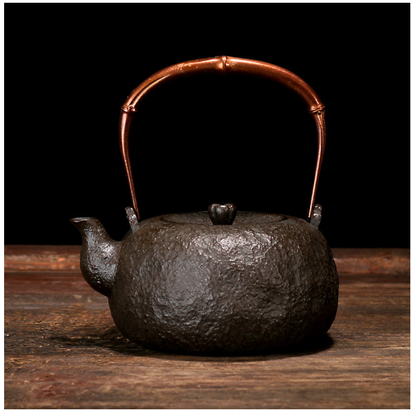 Back view of cast iron teapot against dark background