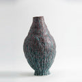 Tall textured ceramic vase with rustic bark finish and teal glaze