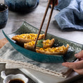 Close up of deep teal curved ceramic platter holding corn sushi with chopsticks