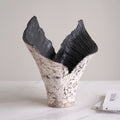 Side view of sculptural ceramic vase on marble table