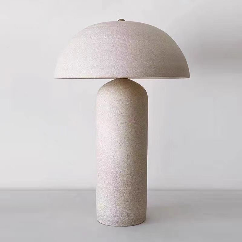 Full view of beige ceramic table lamp with dome shade against white background