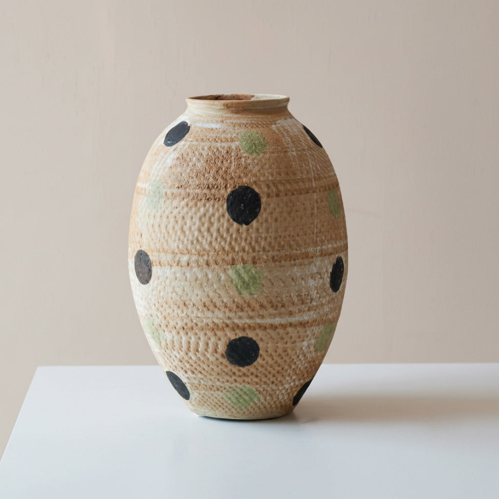 Close up of medium beige textured vase with polka dot pattern