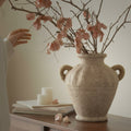 Lifestyle shot of beige vase on wooden console with dried flowers