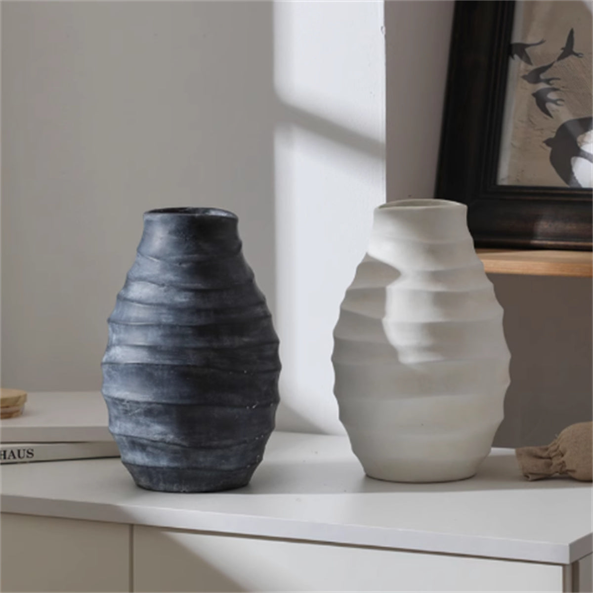 Matte black and white textured ceramic vases on a white shelf