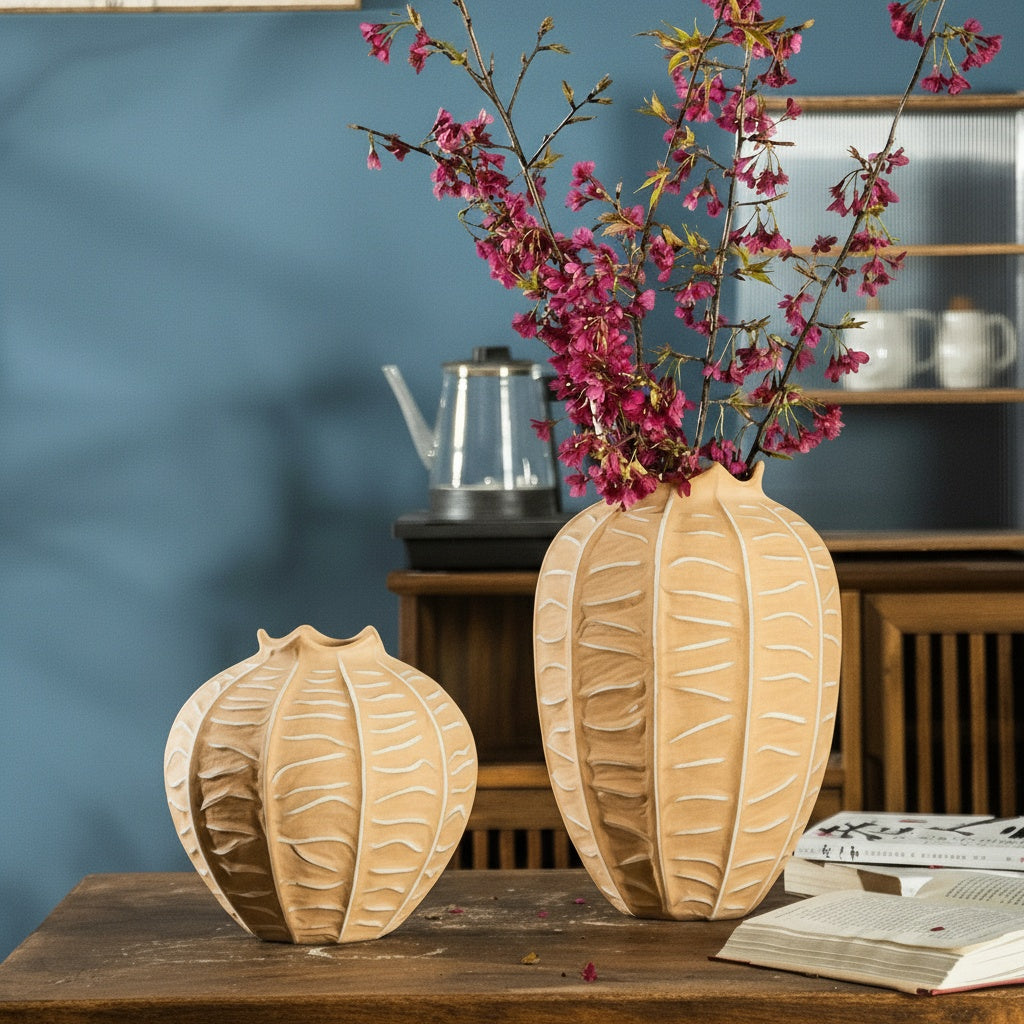 Two textured clay ribbed vases displayed on a wooden table with flowers