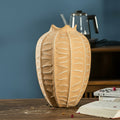 Large textured clay ribbed vase standing on a wooden surface