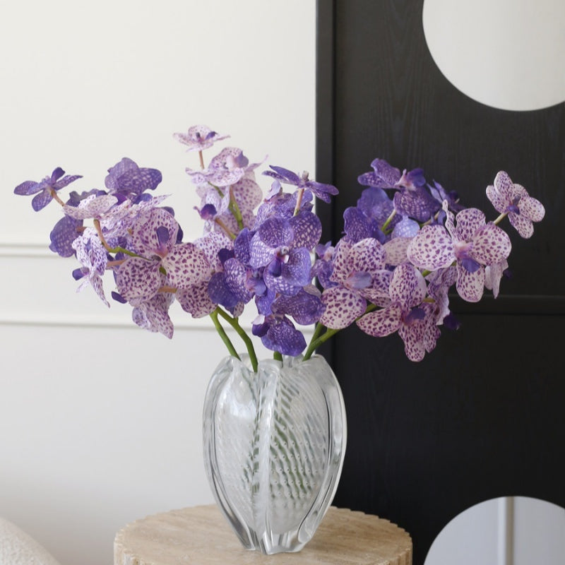 Textured clear glass vase with purple orchids