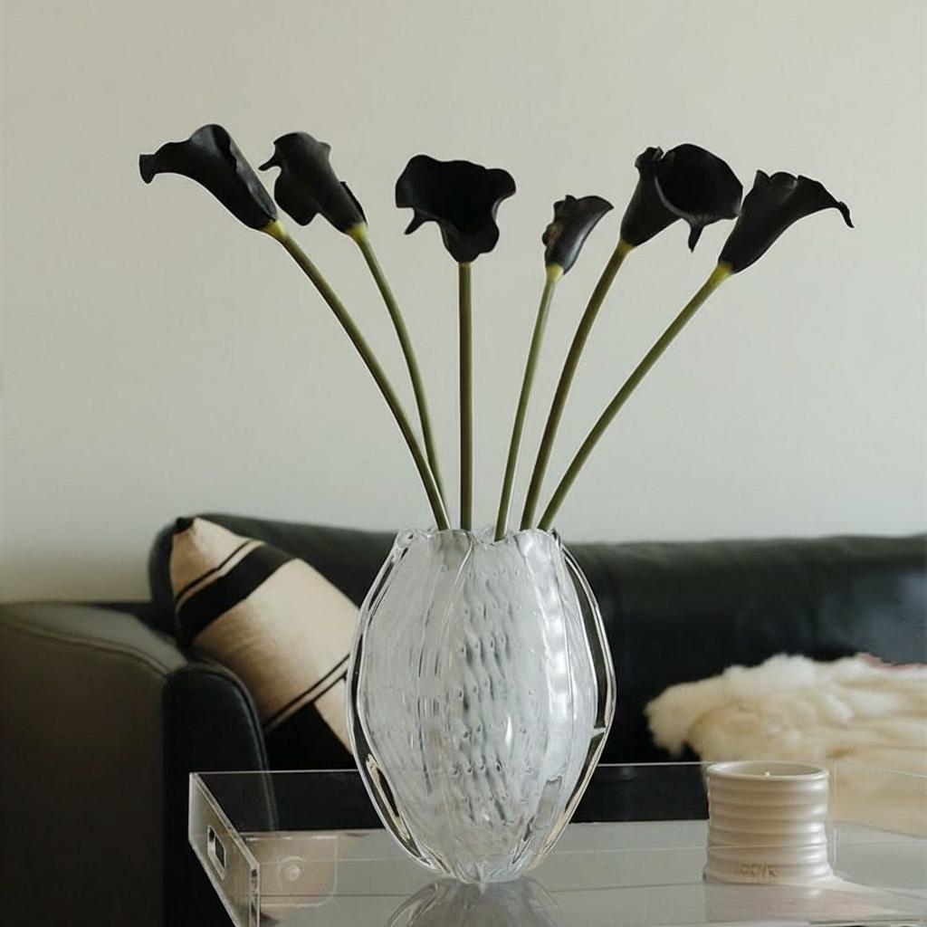 Ribbed oval glass vase holding black calla lilies