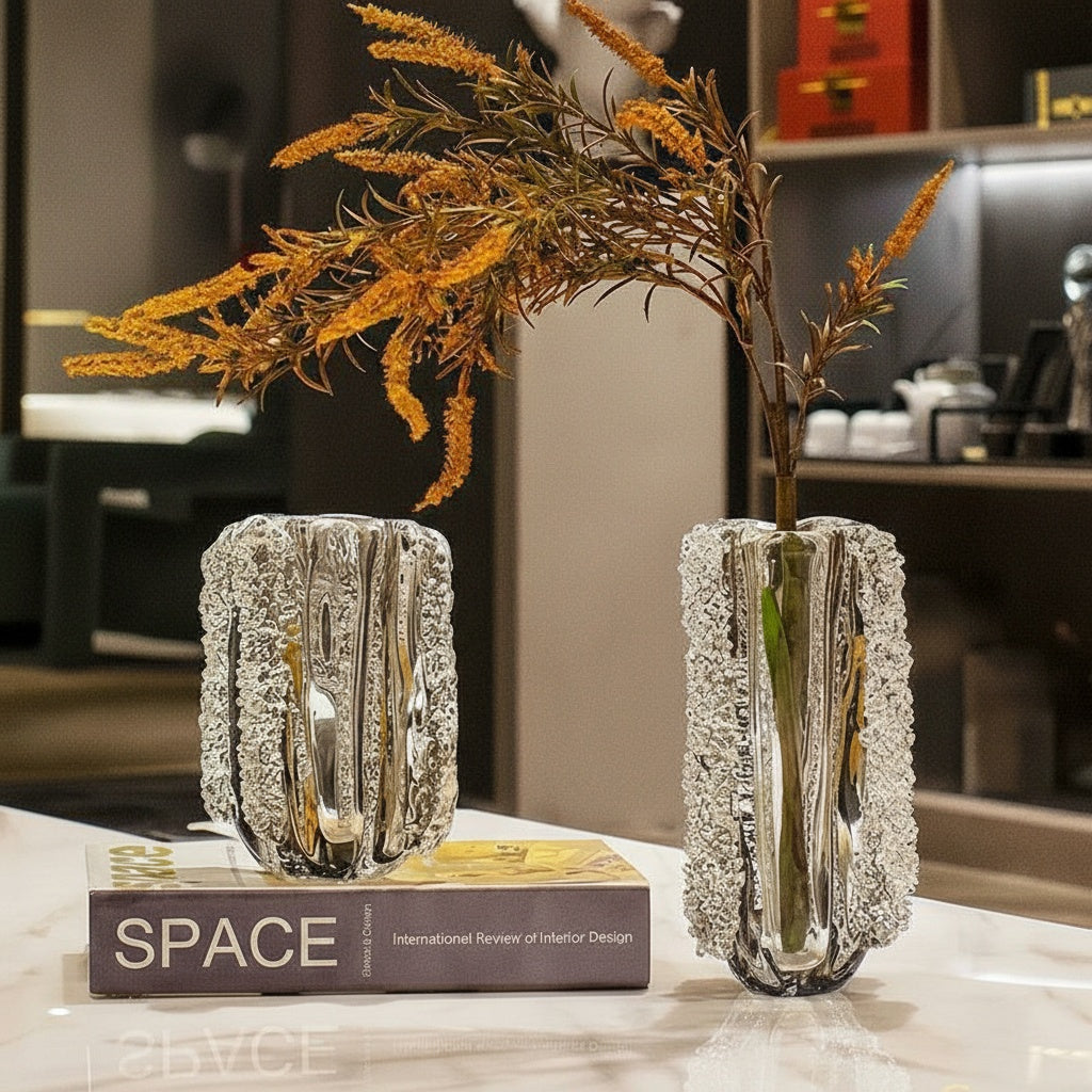 Two textured crystal glass vases on marble table with floral arrangement