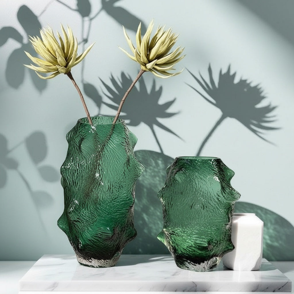 Two organic shaped green glass vases on marble surface