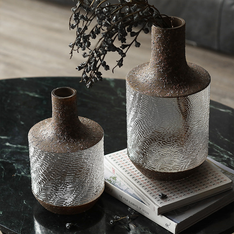 Lifestyle shot of two textured glass vases with rustic details on a coffee table