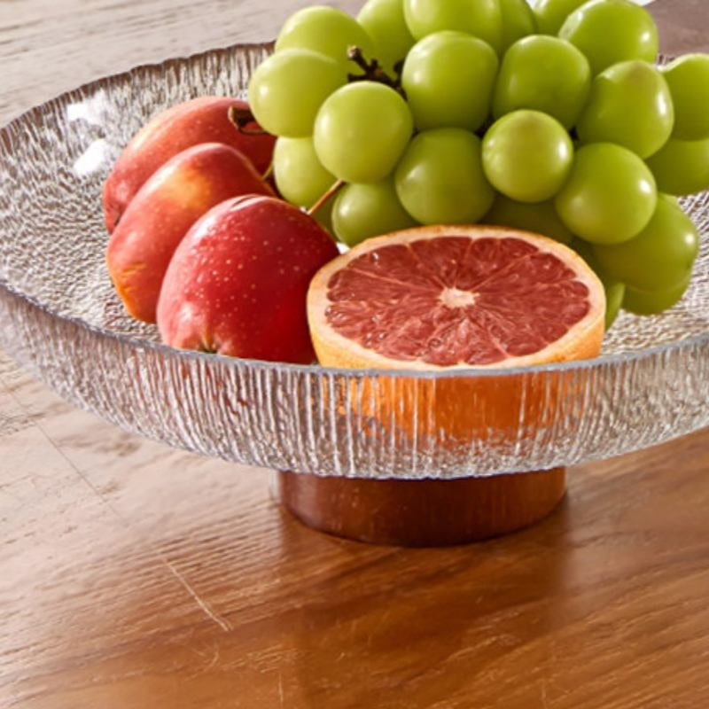Close up of clear glass bowl with fruit on wood table