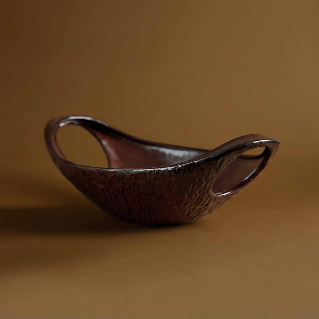 Side view of textured burgundy stoneware bowl with handles
