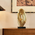 Textured gold twisted oval sculpture on sideboard