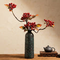 Textured green ceramic vase with red berries