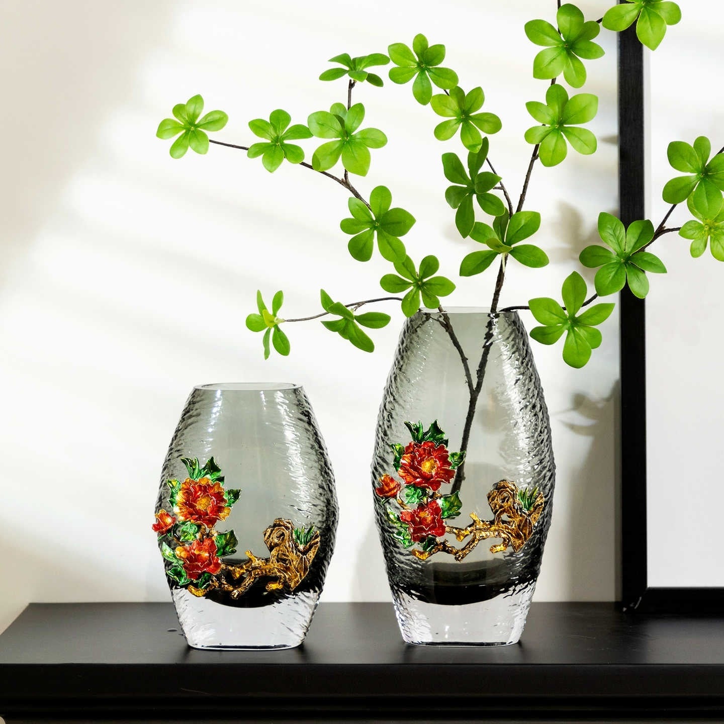 Two grey textured glass vases with enamel flowers side by side