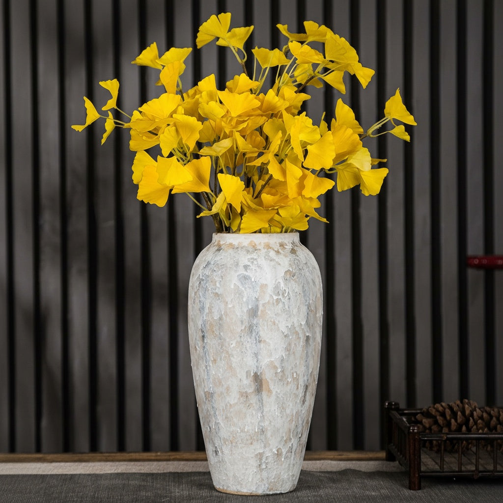Tall white ceramic vase with yellow flowers on dark background