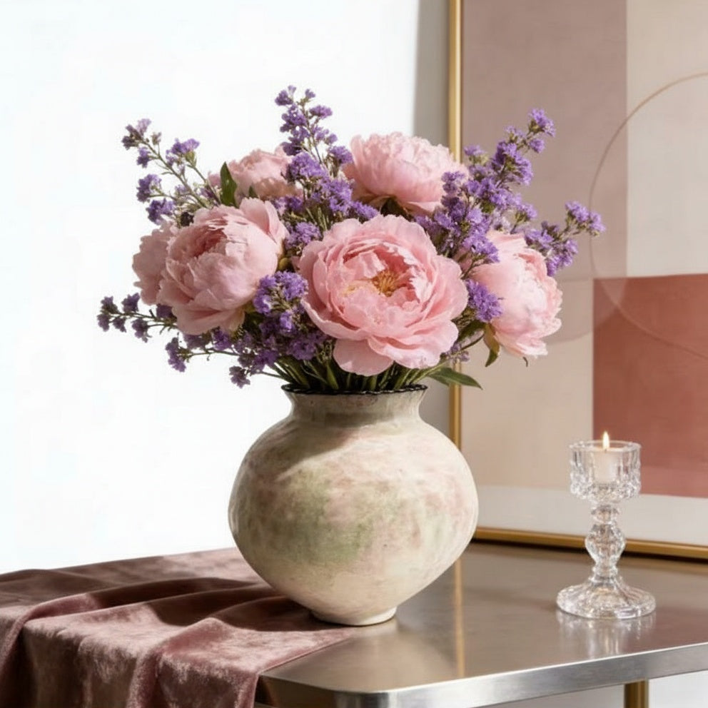 Pink and green ceramic vase holding bouquet of pink peonies