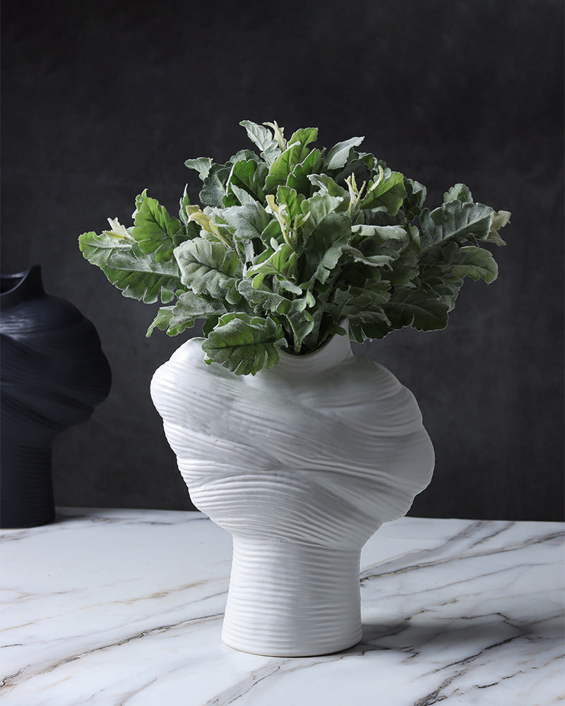 White sculptural porcelain vase styled with green foliage