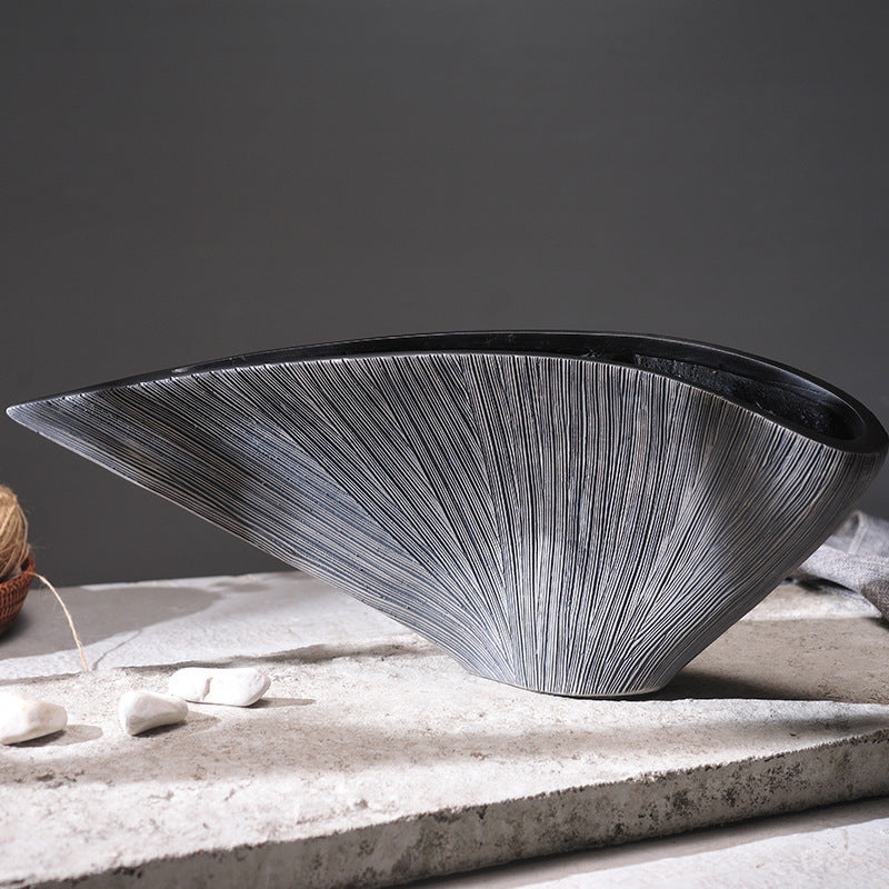 Side view of asymmetric textured silver resin vessel