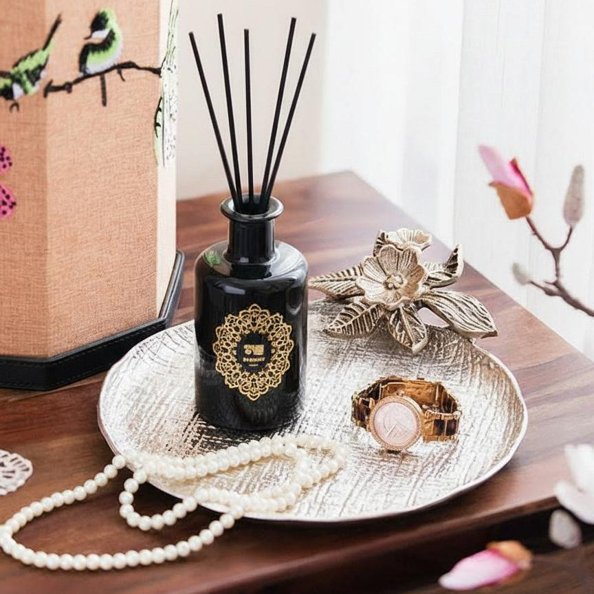 Textured silver decorative tray holding reed diffuser and jewelry on wooden table