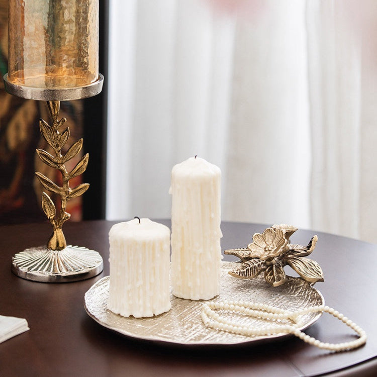 Silver vanity tray displaying white pillar candles and pearls in a luxury setting
