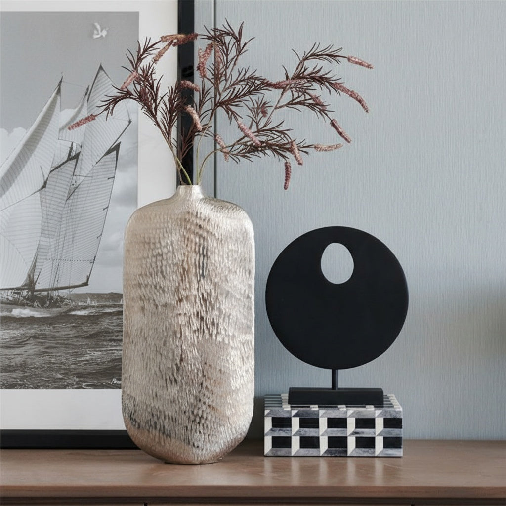 Tall textured silver vase with dried flowers on sideboard