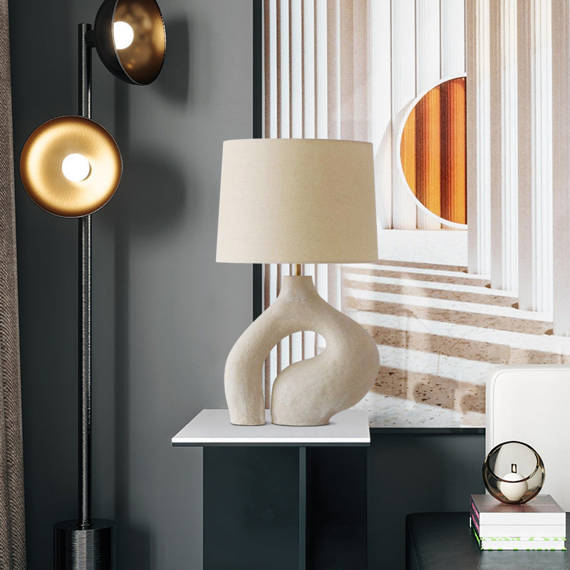 Front view of organic beige ceramic table lamp lit up