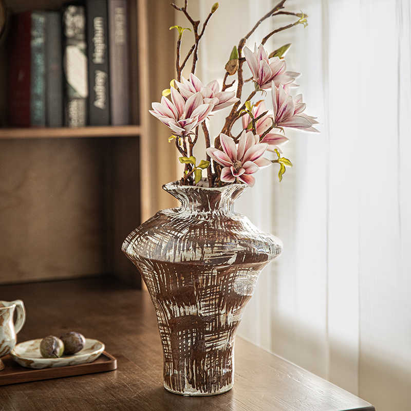 Front view of brown and white textured stoneware vase with magnolia flowers