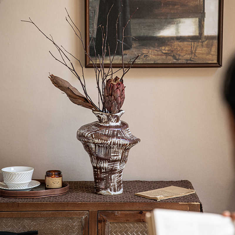 Side angle of sculptural stoneware vase showing cross-hatch pattern on wooden table