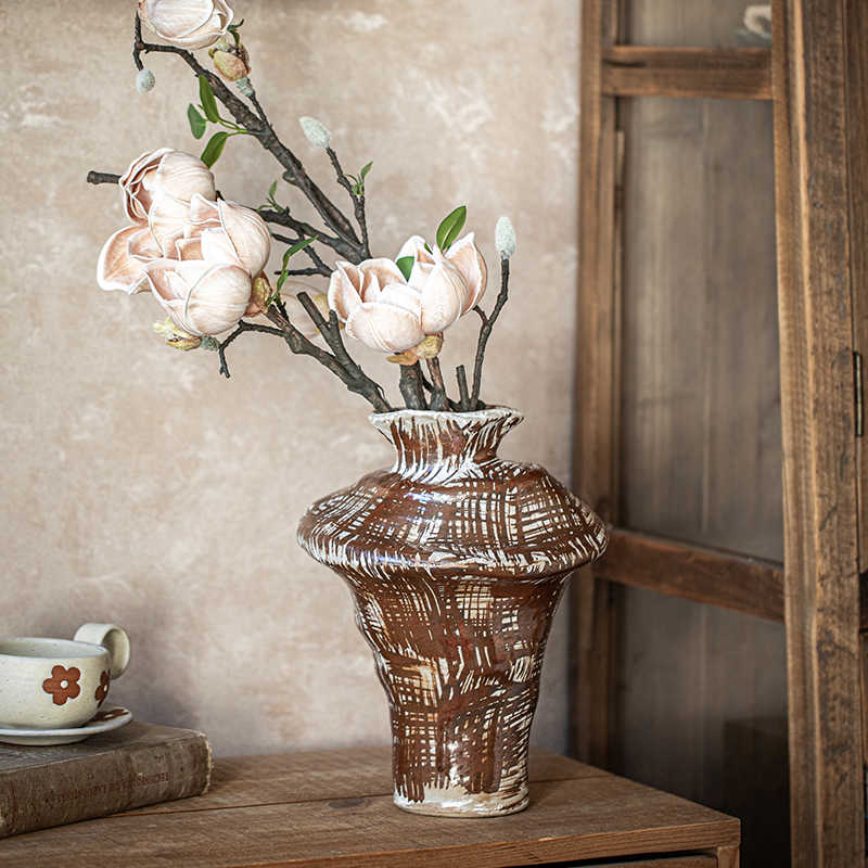 Detail view of textured stoneware vase rim and finish with flowers
