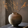 Textured stoneware spherical vase on a dark wooden table
