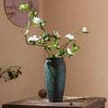 Textured teal ceramic vase holding white flowers on table