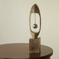 Front view of textured wood sculpture with suspended chrome sphere