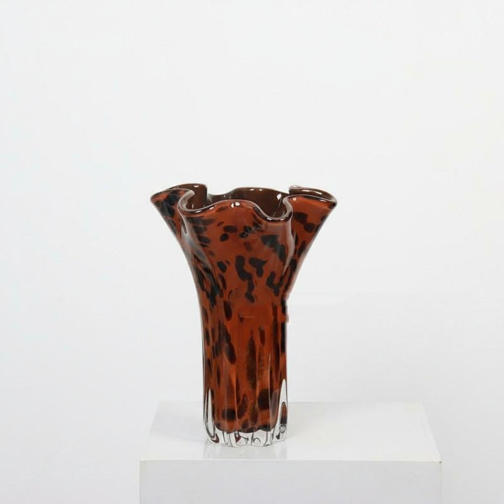 Front view of tortoise shell pattern glass vase on white pedestal