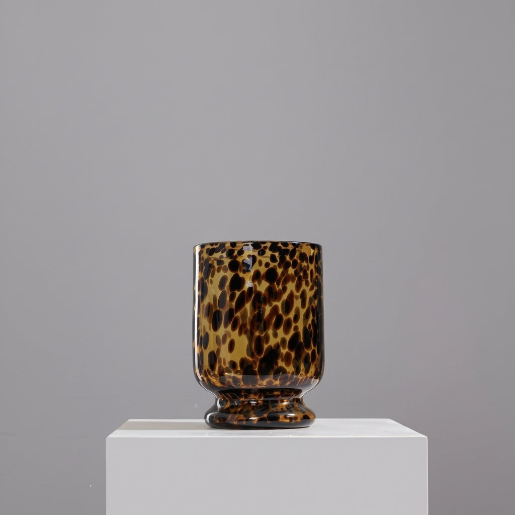 Empty tortoiseshell glass footed vase on a white pedestal