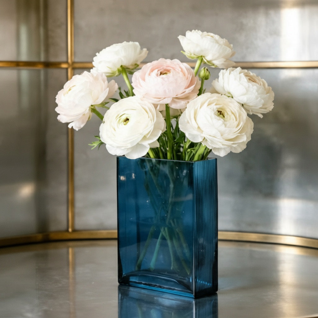 Blue translucent glass curved rectangular vase with white ranunculus flowers