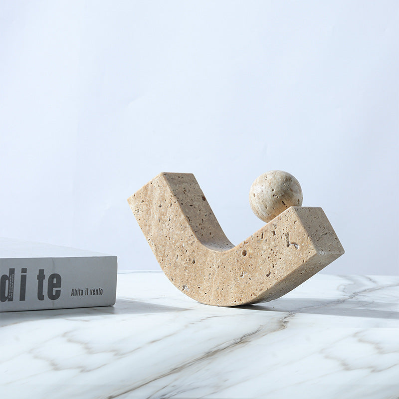 Beige travertine sculpture on marble surface