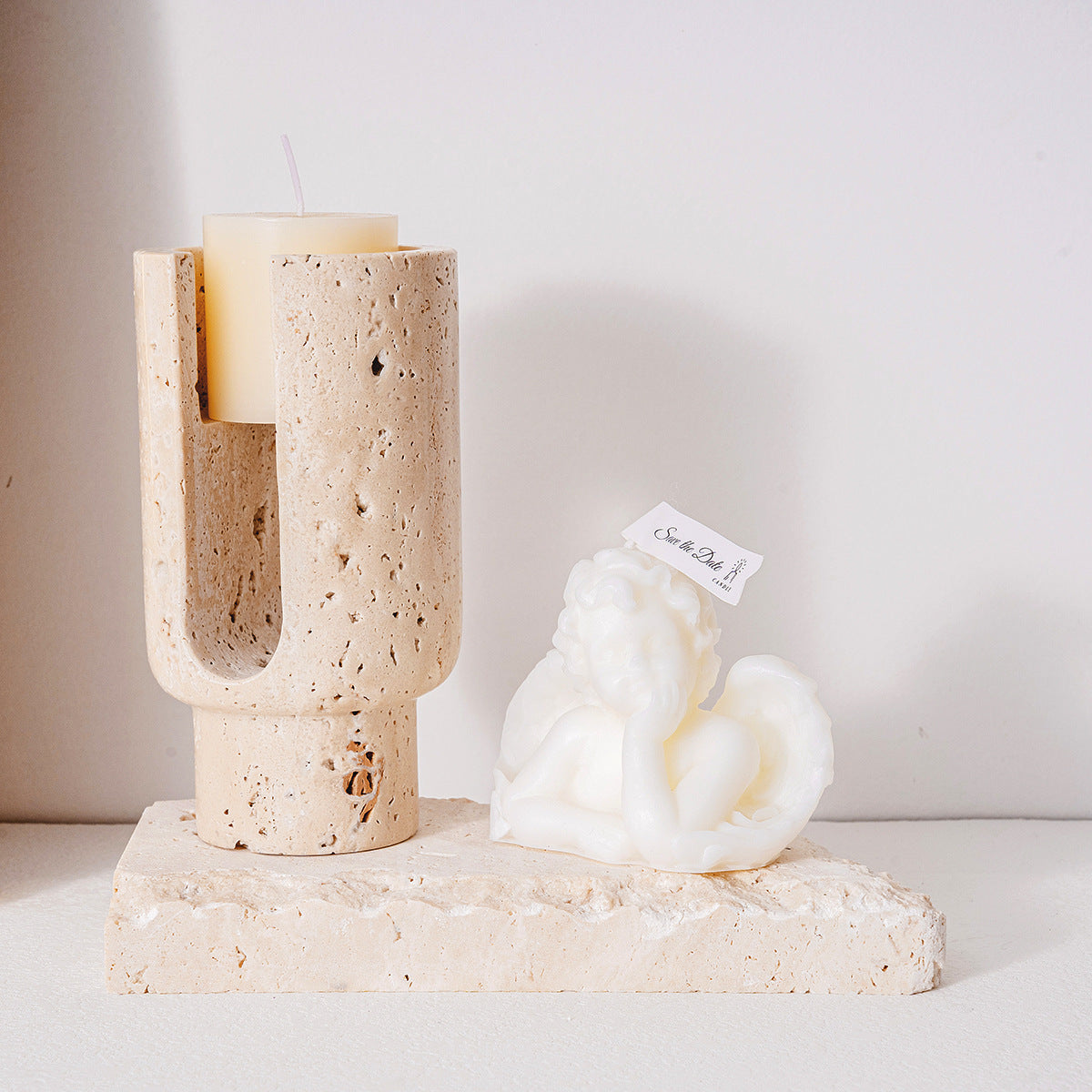 Natural beige travertine candle holder on stone slab with angel candle, showcasing styling potential